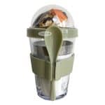 Yoghurtijs met vers fruit en granola in een plastic beker met deksel en lepel.