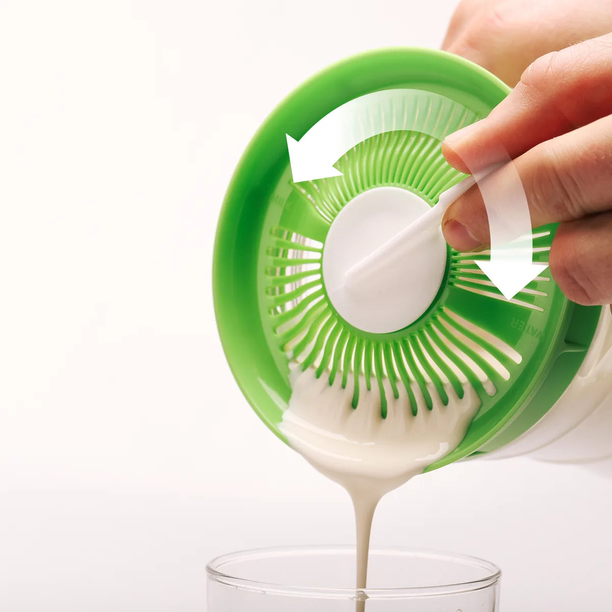 Kefir met de schraper door het zeefdeksel schenken